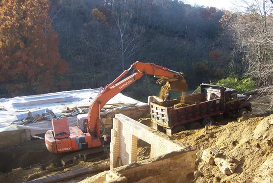 An excavator loading dirt into a dump truck